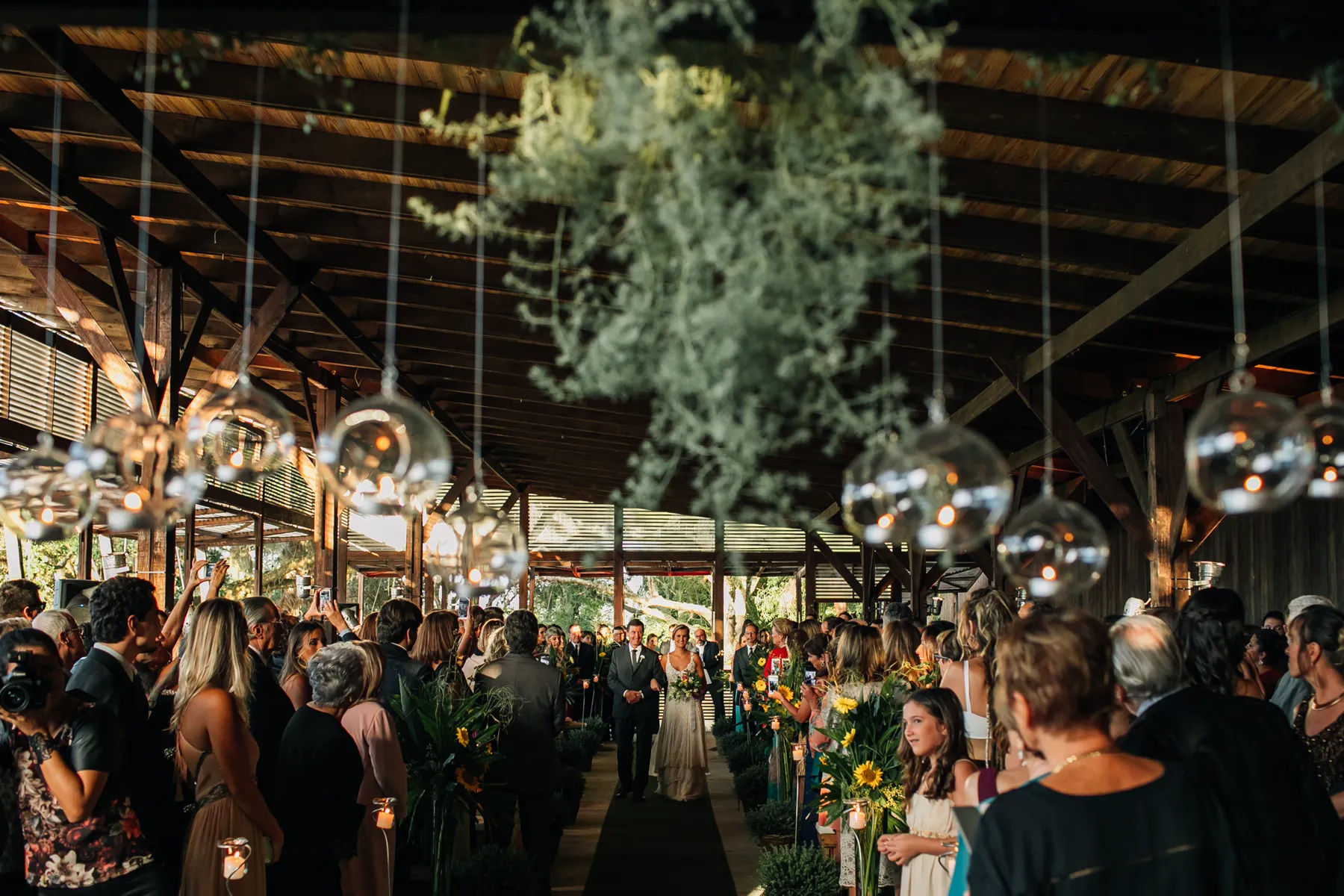 Cerimônia de casamento sob o salão coberto do Butiá, com flores no corredor