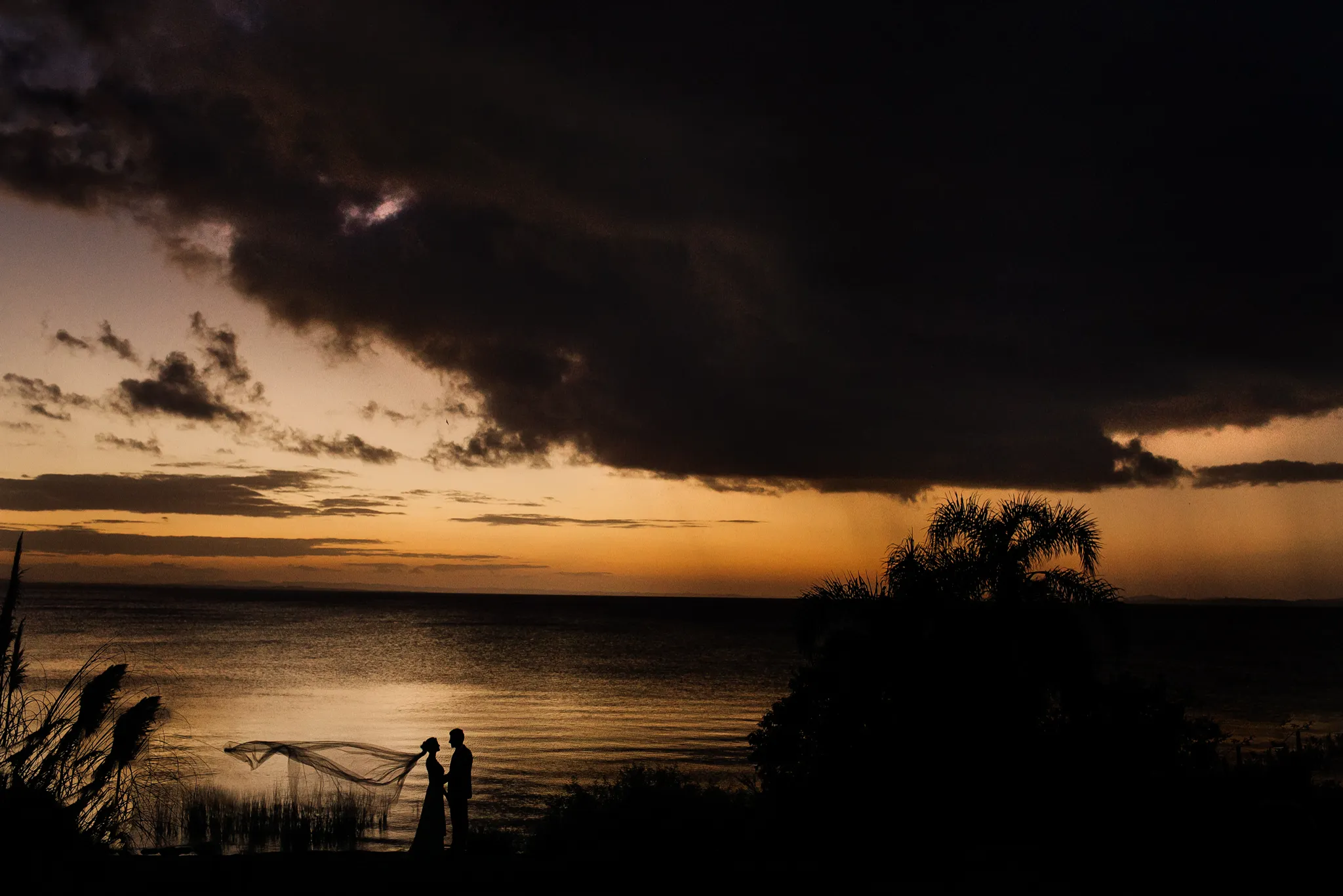 Silhueta de um casal ao pôr do sol à beira do Guaíba